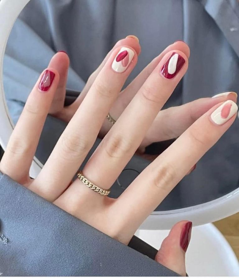Red and cream nail design with heart accents