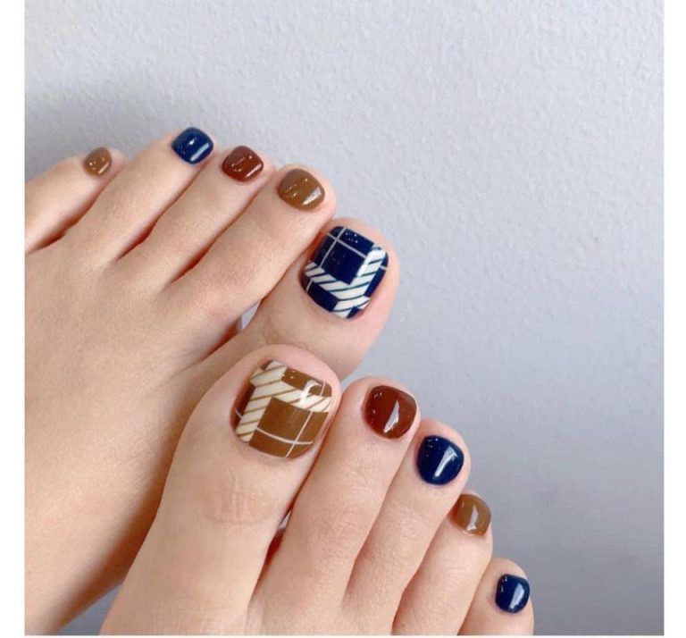 Navy and brown toenail design with white geometric accents
